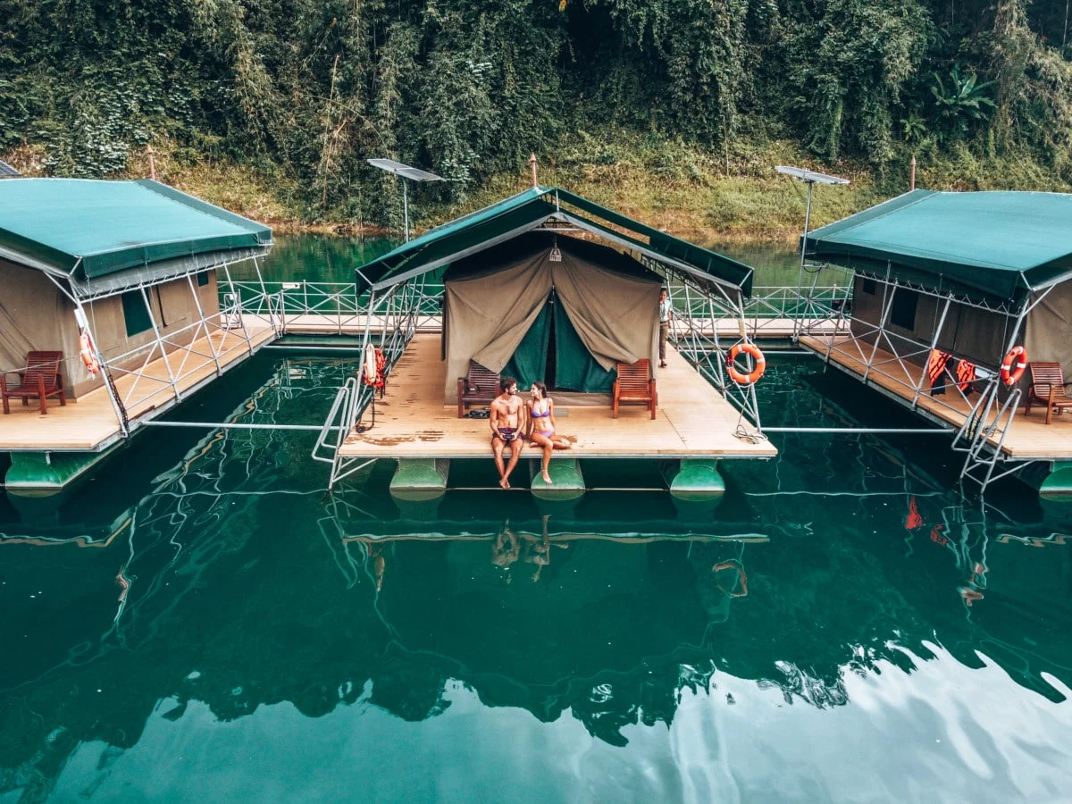 Floating tented bungalows on the still jade waters of Cheow Lan Lake, rainforest behind