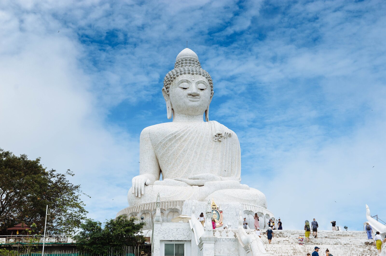 The white marble Big Buddha of Phuket towering over visitors on the ridge