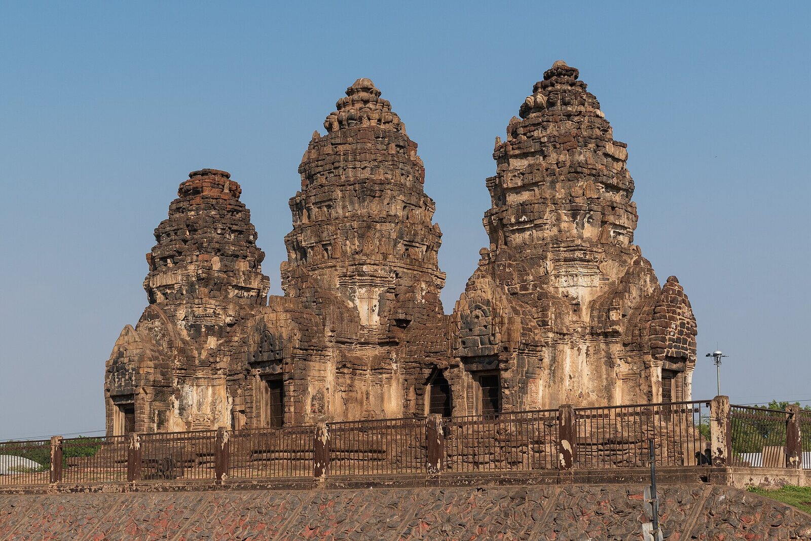 The three Khmer prangs of Phra Prang Sam Yot behind a railing, Lopburi