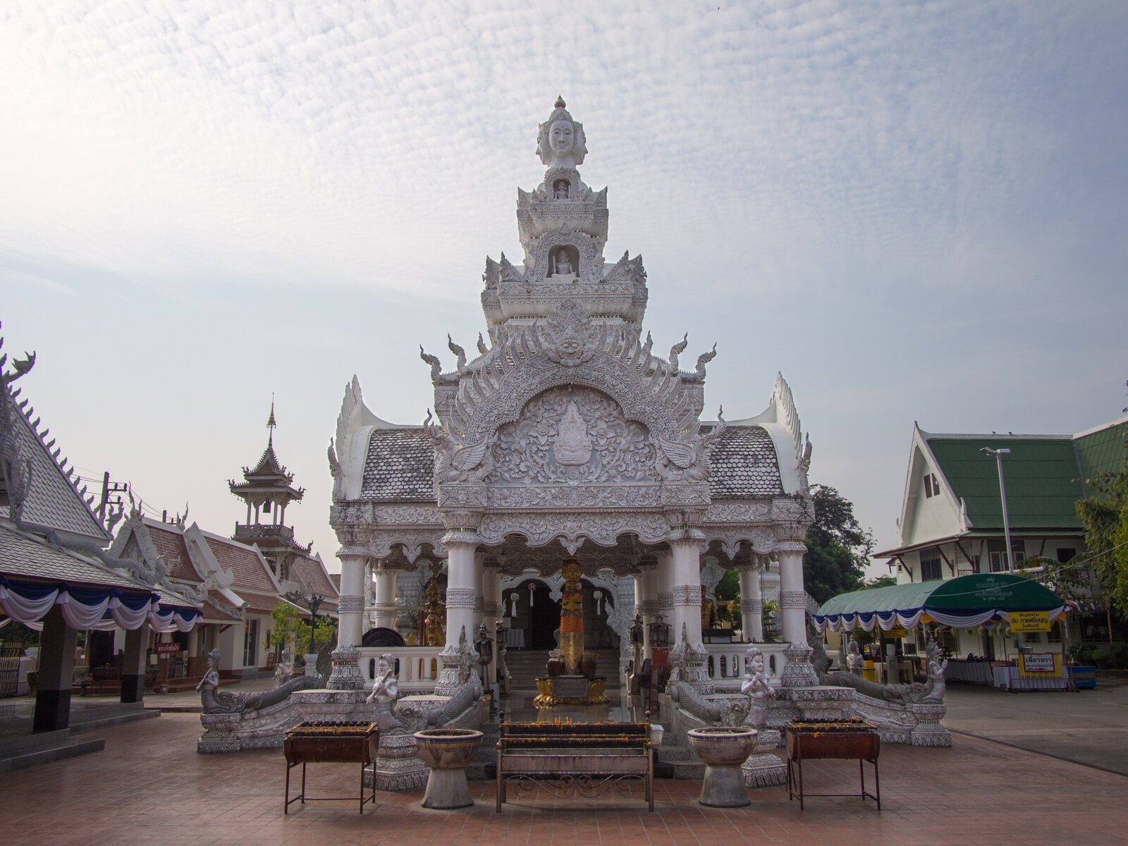 The white, tiered spire of a shrine at Wat Ming Mueang, flanked by naga balustrades, Nan