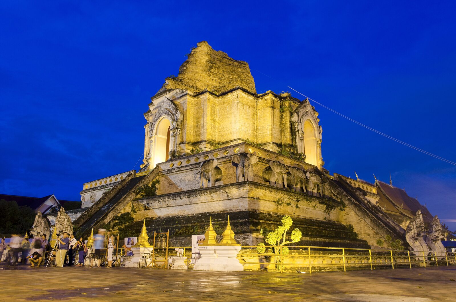 Wat Chedi Luang's broken chedi lit gold at dusk, elephant reliefs around its base, Chiang Mai
