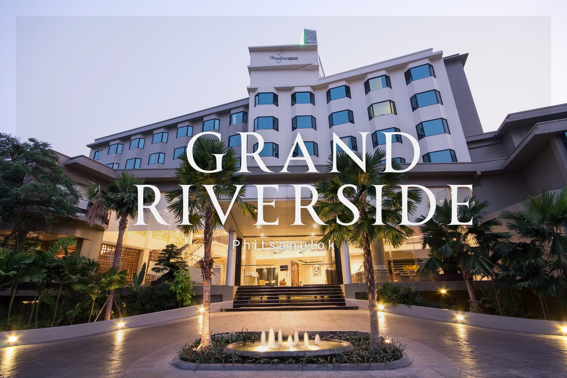 The hotel's tiered facade at dusk with a fountain and palm-lined entrance approach, GRAND RIVERSIDE Phitsanulok lettering overlaid across the frame.