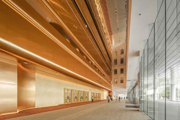 A smooth grey concrete wall carrying the venue's gold emblem above its name in Thai script and, beneath, "QUEEN SIRIKIT NATIONAL CONVENTION CENTER" in gold lettering.