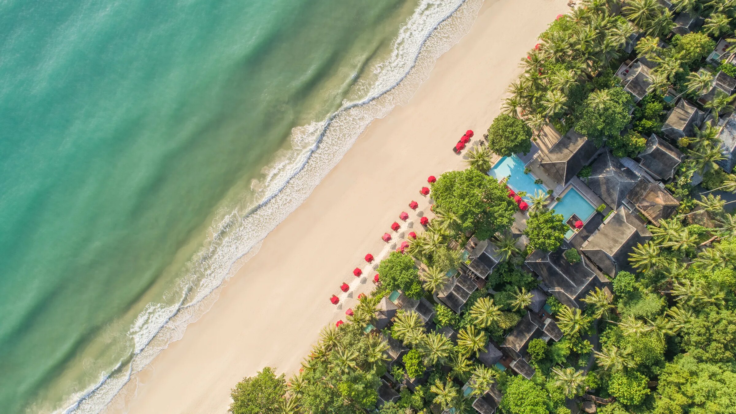Anantara Rasananda from the air — the beach, its red umbrellas, the pool and villas under the palms at Thong Nai Pan Noi