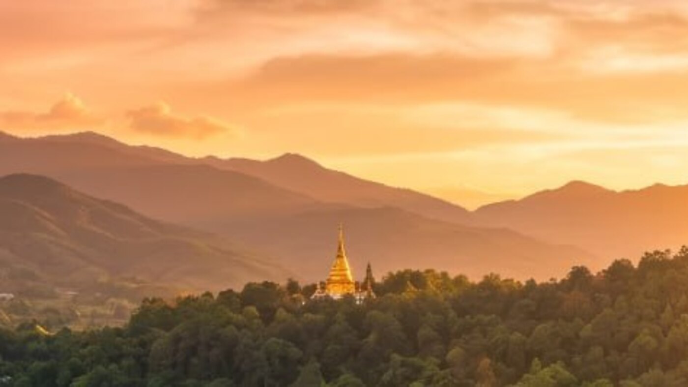 A golden hilltop chedi above the Chiang Mai valley at dusk
