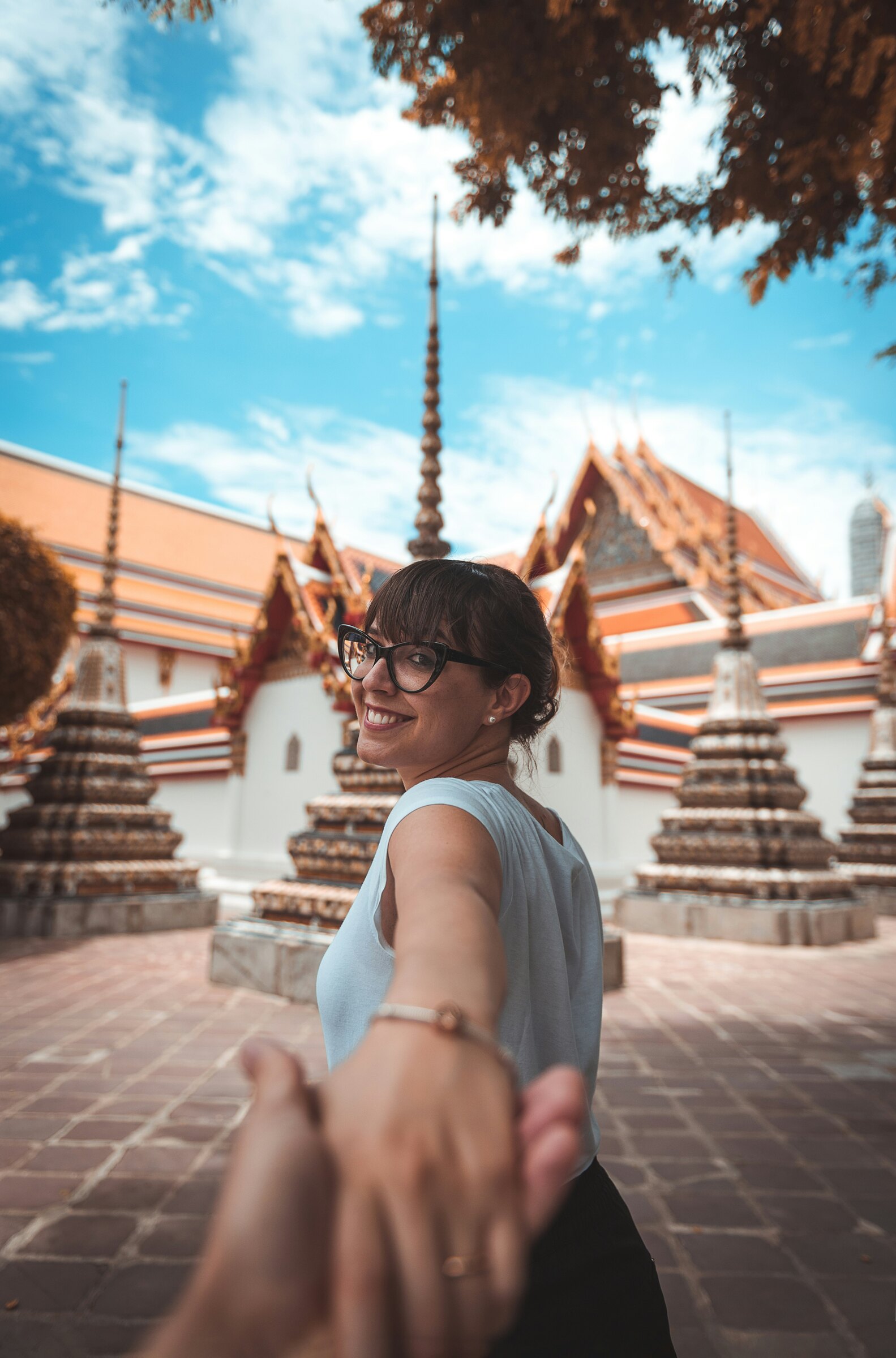 A woman leading by the hand through the tiled chedis of Wat Pho, Bangkok