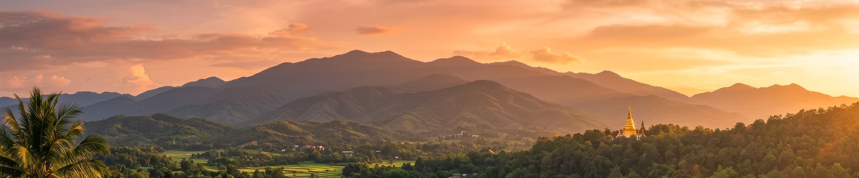 Mountain ridges at sunset with a golden pagoda, northern Thailand