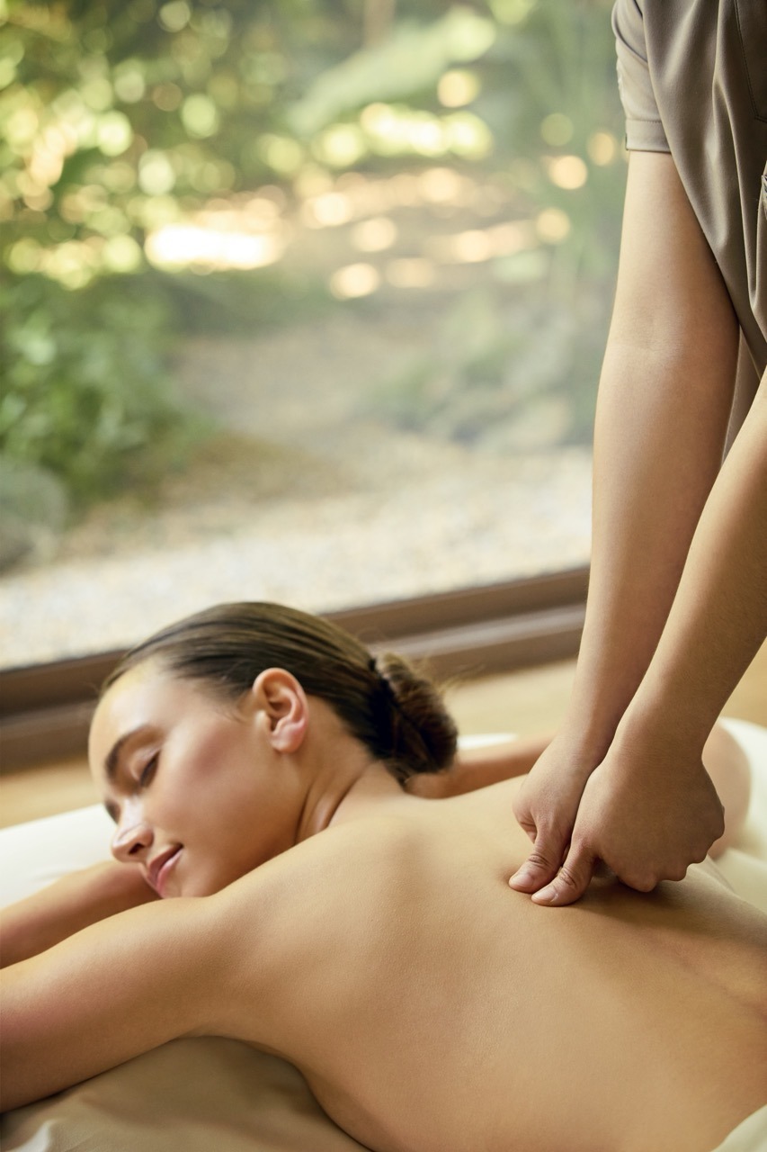 A massage treatment beside a window looking onto garden and dappled light