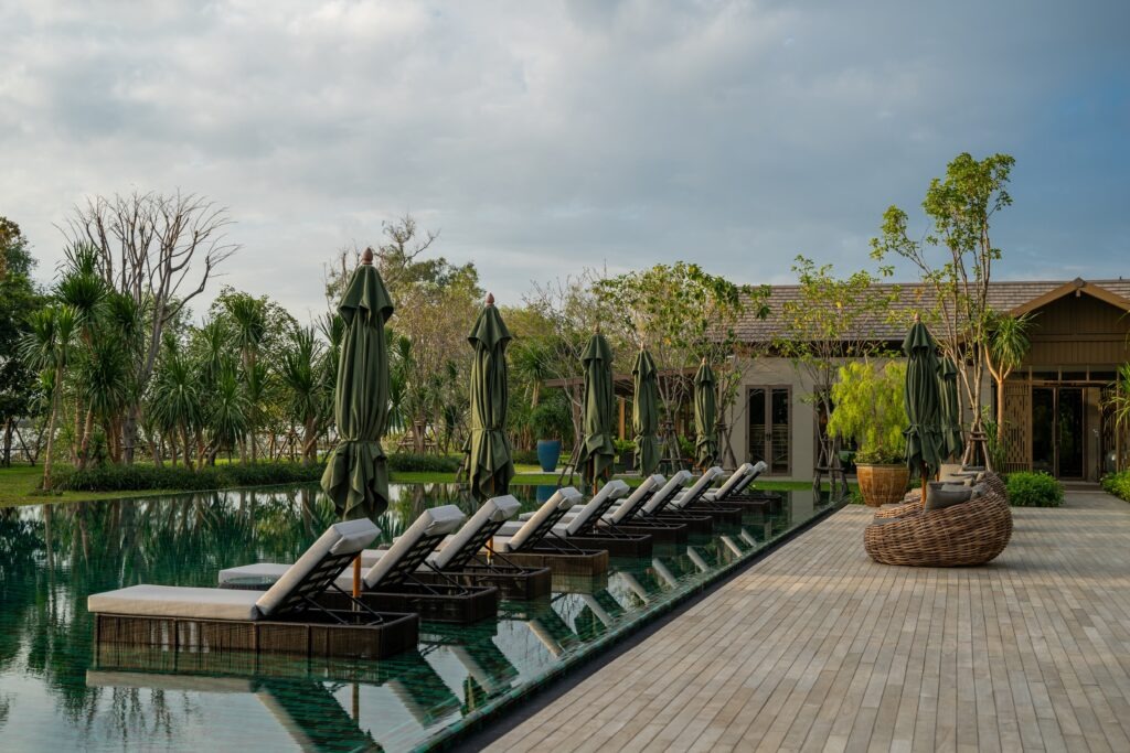 Loungers and green parasols beside a long pool at RAKxa, Bang Krachao