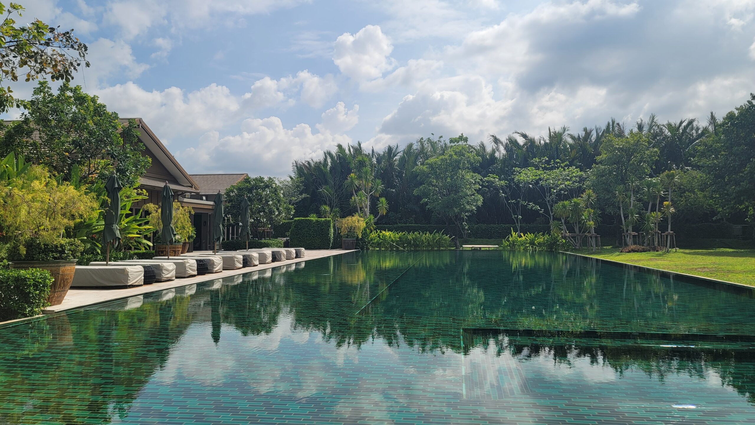 The long green-tiled pool and lawn at RAKxa, Bang Krachao