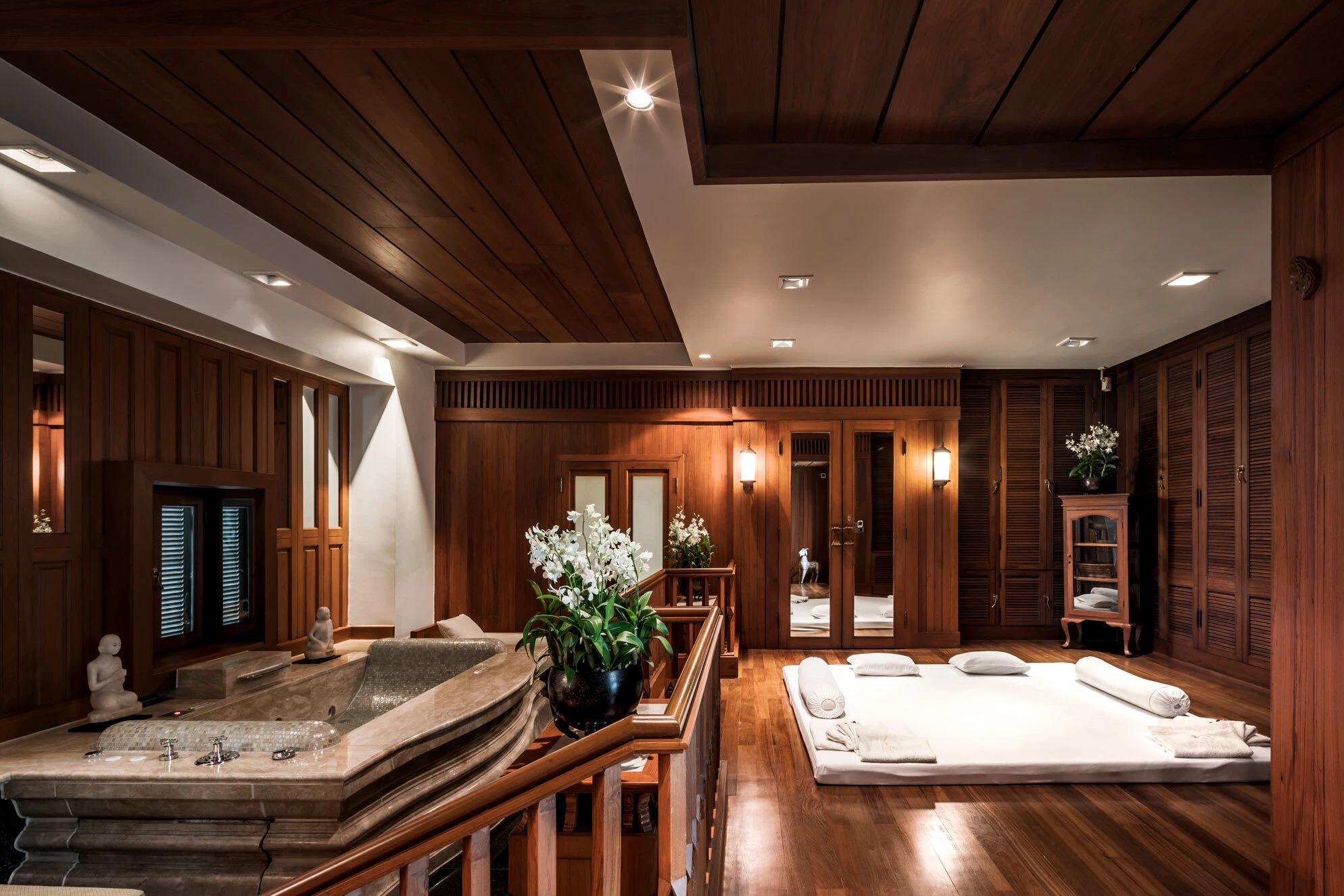 A teak treatment suite with floor mattresses and a stone bath
