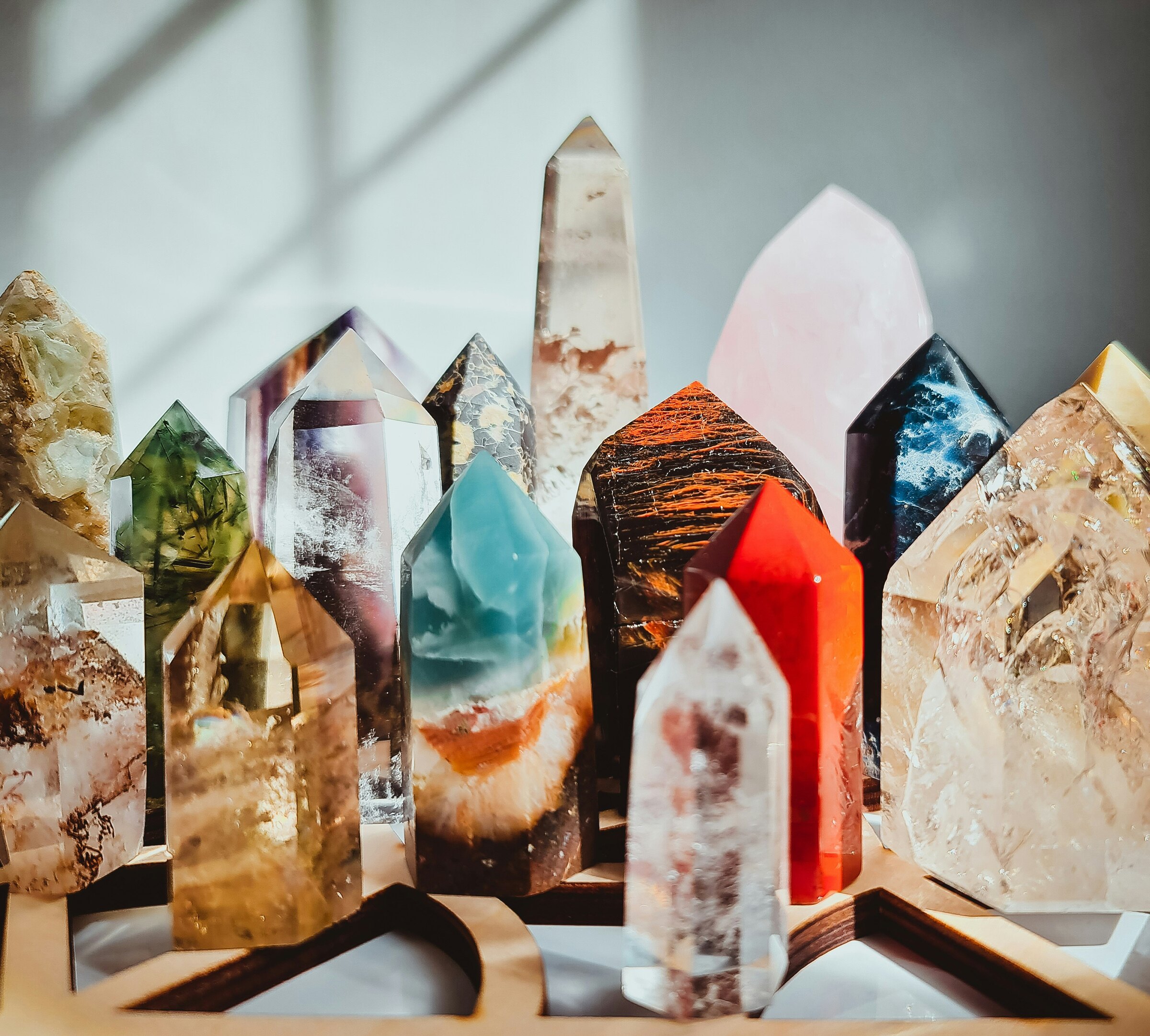 Polished crystal points standing on a wooden tray in window light