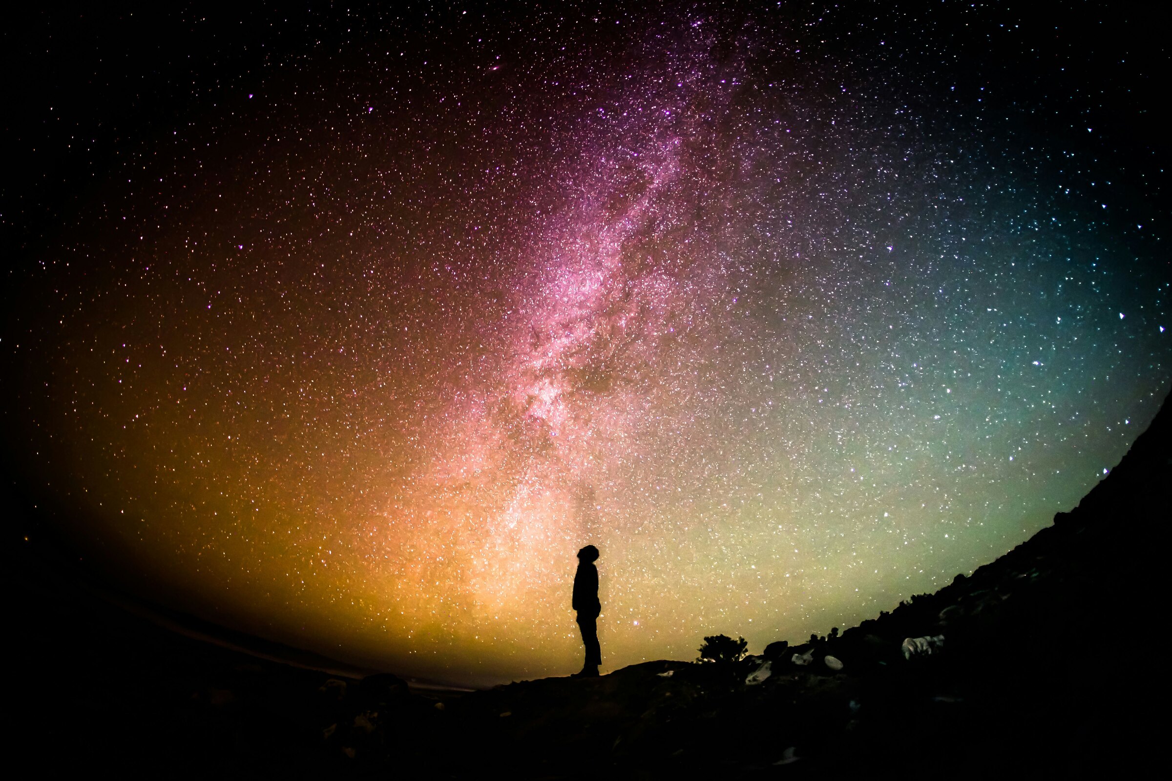 A lone figure on a ridge under the Milky Way