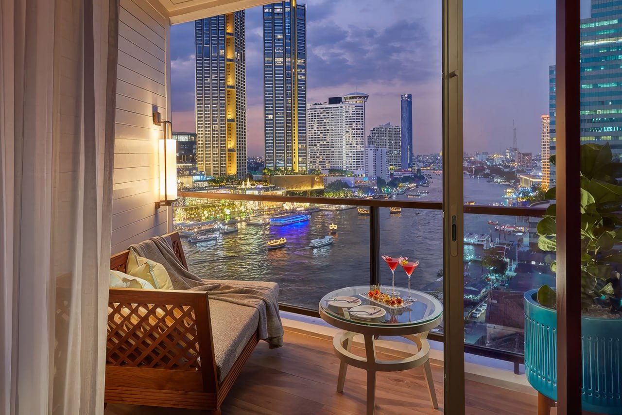 A riverside suite balcony looking out over the Chao Phraya and the city at dusk