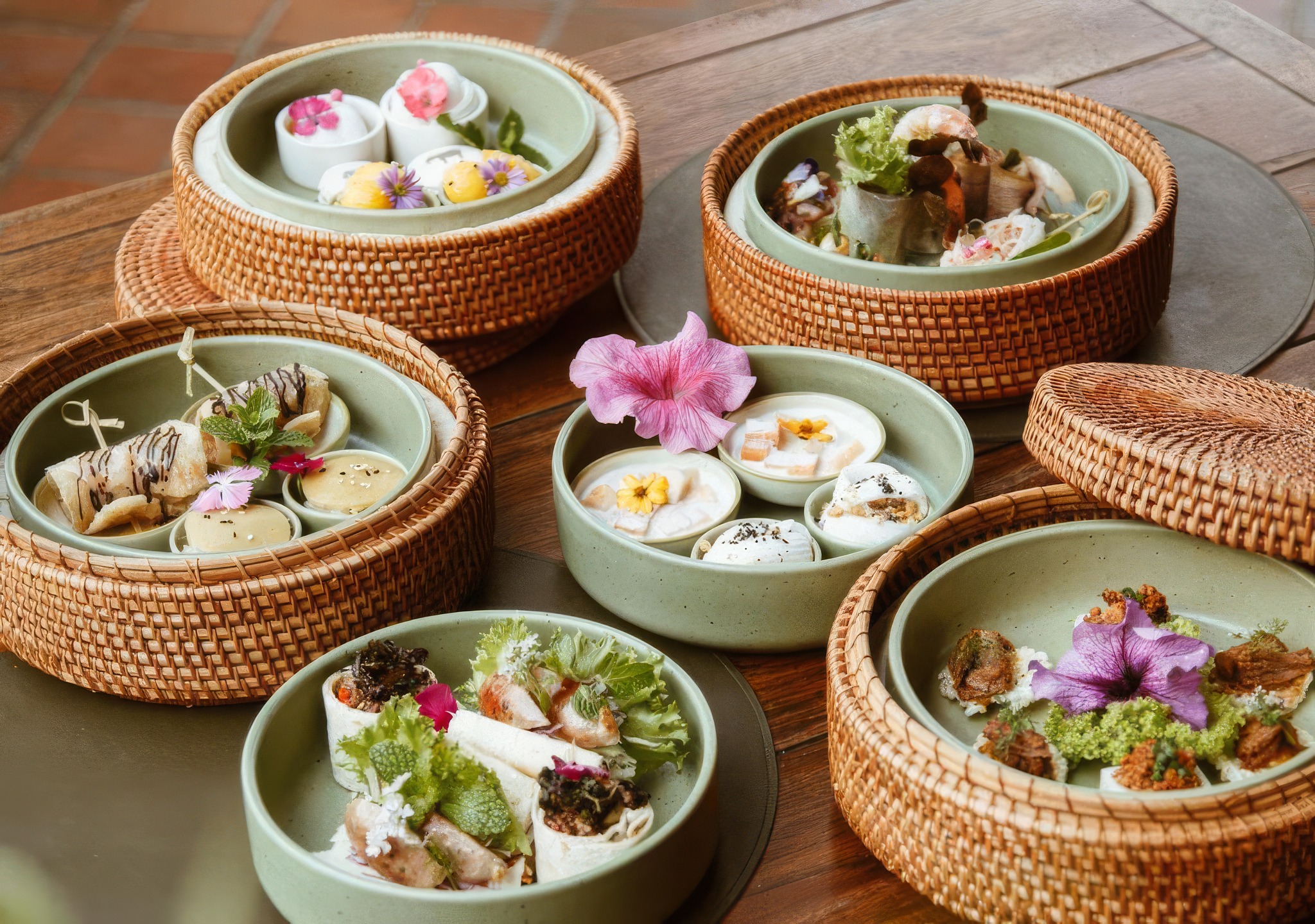 A tasting of Thai canapés served in woven rattan steamers, edible flowers throughout